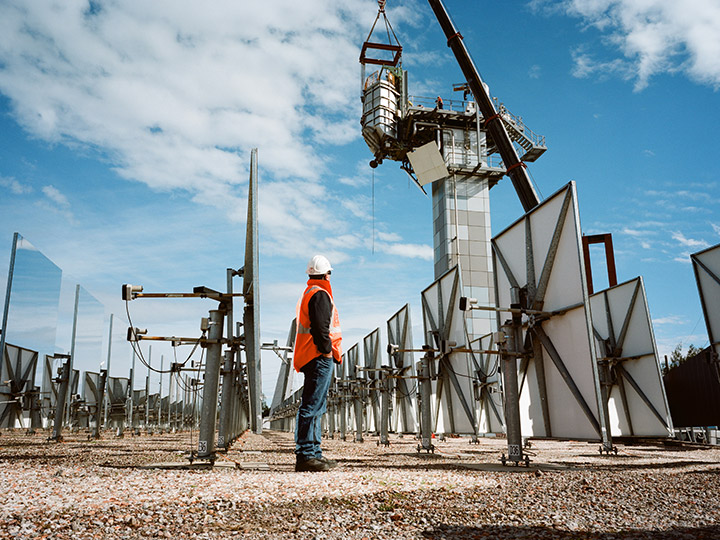 en arbeider står foran en speilgård for innsamling av termisk energi